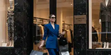Woman leaving luxury fashion store with shopping bags, showcasing membership benefits.